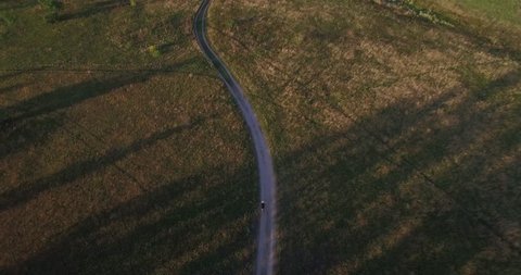 Aerial Cycling MTB Bike Riding From Drone.Cyclist Senior Man Riding Mountain Bike.Athlete Training Along Country Road.Man On Gravel Bicycle Aerial Drone View.Cycling In Sunset From Above.Sport Concept