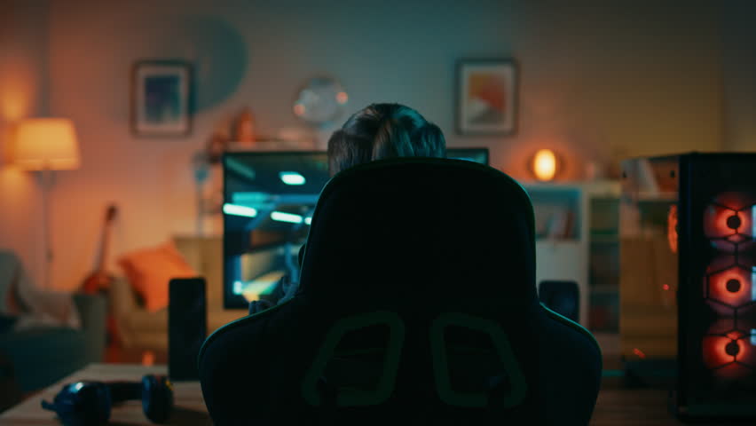 Back Shot of a Gamer Playing and Winning in First-Person Shooter Online Video Game on His Powerful Personal Computer. Room and PC have Colorful Neon Led Lights. Cozy Evening at Home. | Shutterstock HD Video #1020758392