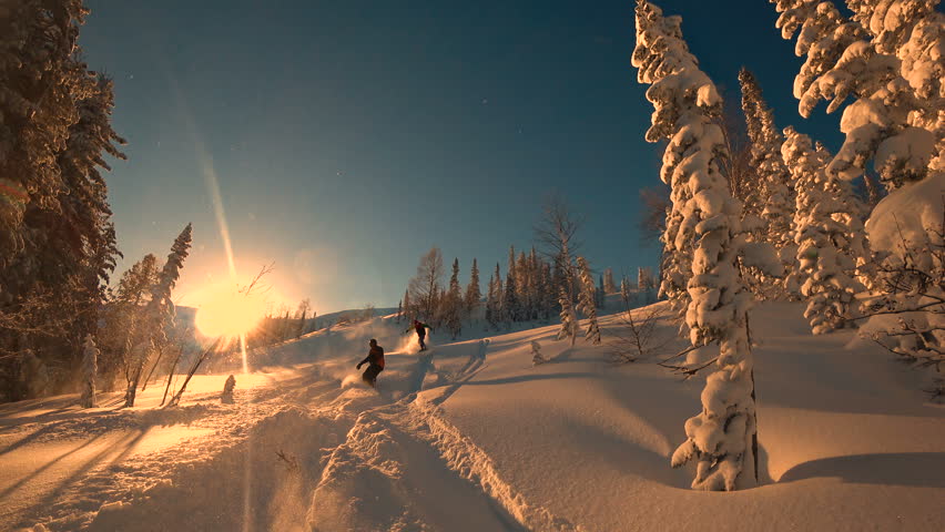snowboarders quickly go down to the camera among the beautiful taiga in the light of the Golden sunset. 4k super quality
