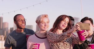 Group of friends taking selfie with city skyline in background