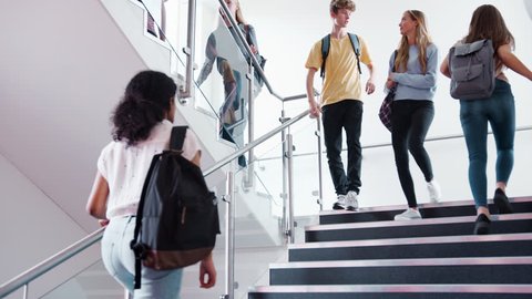 High School Students And Staff Walking On Stairs Between Lessons In Busy College Building