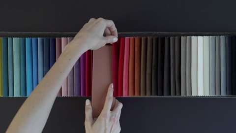 Woman applies a tile sample to samples of designer velvet. Designer selects the color of textiles to match the color of the walls. Girl chooses an appropriate color for a interior design project. 