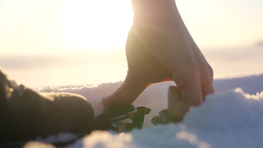 Skier putting on skis, close-up on sunset background