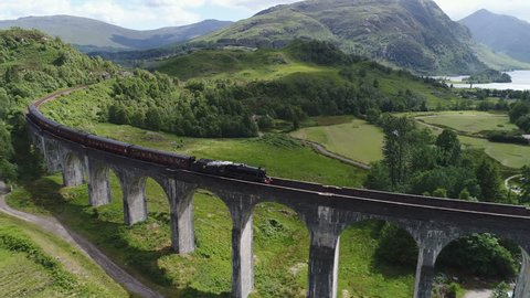 Drone shot of classic steam train crossing the famous historic Glenfinnan viaduct, travel and tourism Scotland