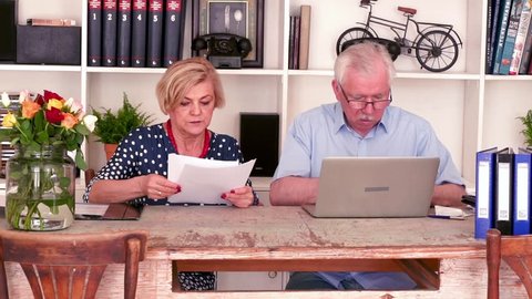 15.04 2018 Krakow,Poland: Mature couple counting bills with laptop by table at home
