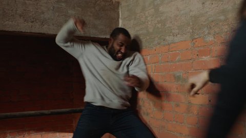 Black man chases a white man up an industrial staircase where they begin to fight in moody lighting. Medium shot in 4K with an Alexa Mini camera