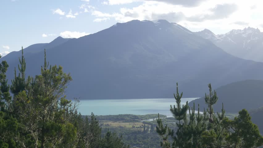 A mountain is behind some mist with a lake at the bottom.