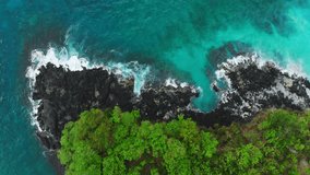 Aerial view of blue ocean and black rocks in tropical island.