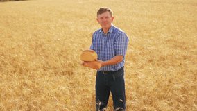old farmer man baker holds a golden bread and loaf in ripe wheat field. slow motion video. 