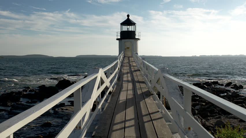 Maine coastline lighthouse with long wooden boardwalk leading out over the water.