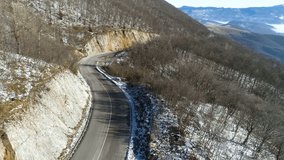 This stock video features a bird's eye view of an aerial view of a winter mountain road. The camera adjusts its angle and becomes a top view shot. 