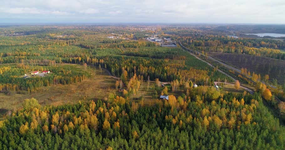 Autumn color countryside,  aerial, tracking, drone shot, sideways over a forest, road and a town, on the countryside, on a sunny, fall day, in Uusimaa, Finland