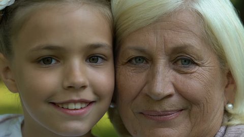 Grandmother and granddaughter looking in camera, generation, faces closeup