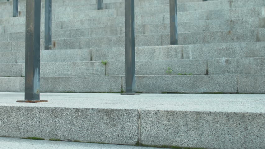 Young woman dressed in jeans and sport shoes going down on stairs, legs close up
