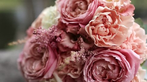 Beautiful bridal bouquet of a roan-colored peony rose next to a pair of gold wedding rings