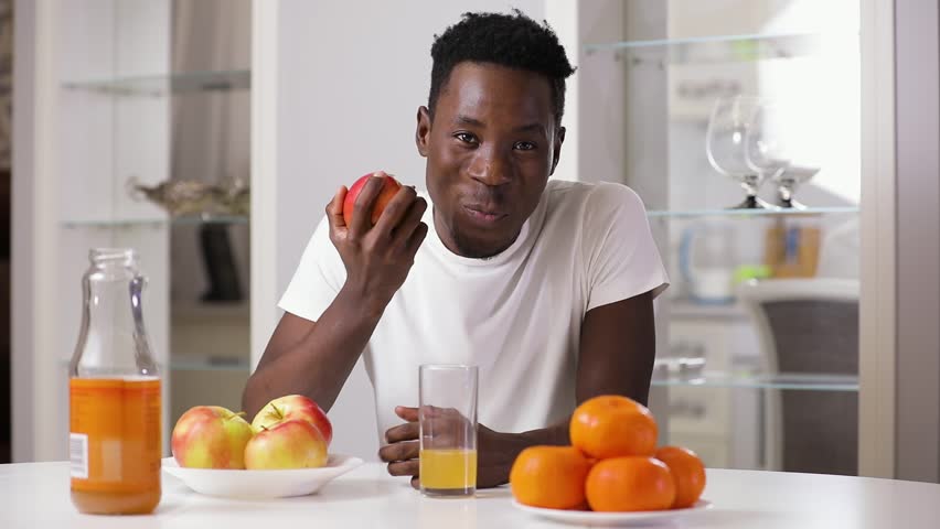 Чернокожий ест. Негр ест яблоко. Мужчина ест персик. Негр ест апельсин.