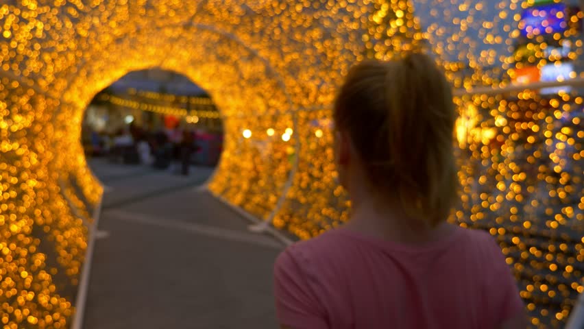 beautiful girl in white shorts goes through a vault of golden lights.