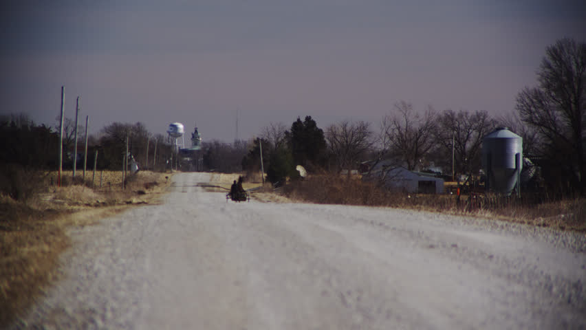 Amish man in a horse drawn buggy travels freely down a gravel road towards Bloomfield in Davis County, Iowa
