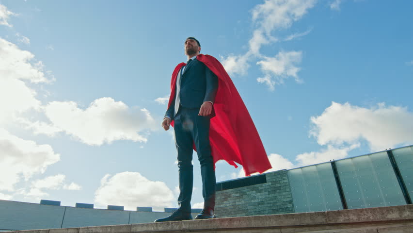 Superhero With Red Cape Blowing in the Wind Stands on the Roof of a Skyscraper, Crossed Arms, Ready to Make Business Transactions and Save the Day. Low Angle Shot. | Shutterstock HD Video #1020802270