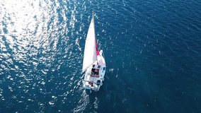 Aerial drone video of small sail boat cruising in deep blue mediterranean sea