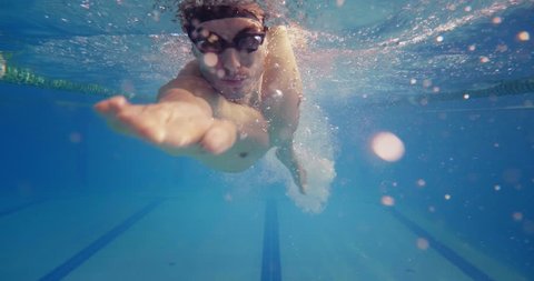 Professional swimmer with googles trains with effort and dedication to win the race by swimming in a freestyle pool. Shot with RED Camera in 8K. Concept of sport, swimming pool, competition, fitness.