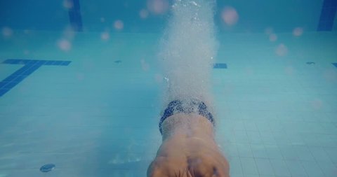 Professional swimmer with googles jumping and diving in a freestyle pool. Shot with RED Camera in 8K. Concept of sport, swimming pool, competition, fitness.