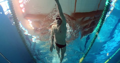 Professional swimmer with googles trains with effort and dedication to win the race by swimming in a freestyle pool. Shot with RED Camera in 8K. Concept of sport, swimming pool, competition, fitness.