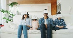 Portrait of happy family using vr glasses in living room in slow motion. Shot with RED camera in 8K. Concept of innovation technology, family entertainment, game