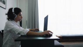 Teenager plays video games. Computer teenager boy with headphones looking at laptop screen