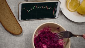 Businesswoman having lunch. On the table is a salad, bread, lemon and tea. She watches online currency quotes on the smartphone screen. Focus on smartphone screen. - Powered by Shutterstock - Get 15% off with code: PIKWIZARD15