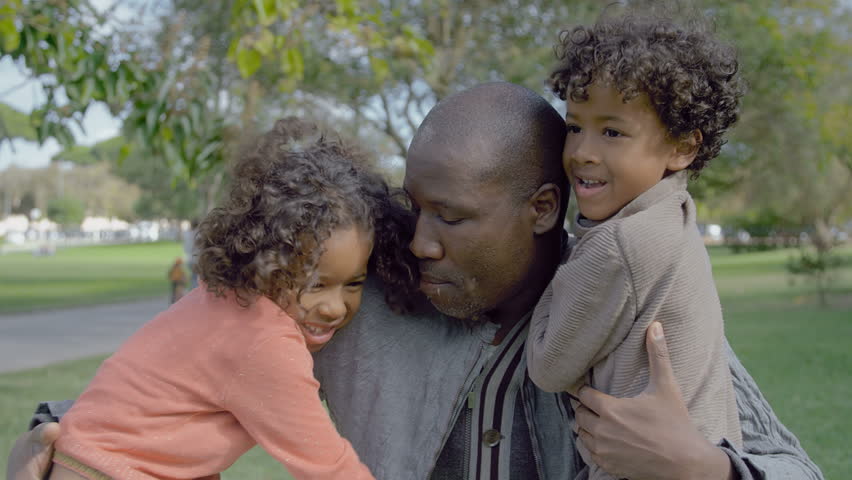 African American dad embracing curly children in summer park. Portrait of happy father hugging adorable little kids in park in slow motion. Family concept Royalty-Free Stock Footage #1020821410