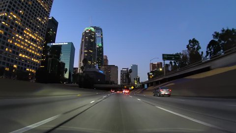 Los Angeles, California, USA - December 8, 2018:  Driving past buildings, bridges, signs and palm trees in light weekend predawn traffic on the Harbor 110 freeway south in downtown L.A. 