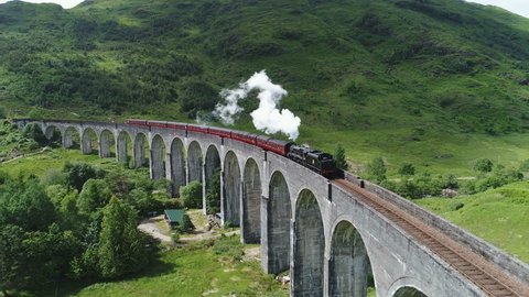 Drone shot of classic steam train crossing the famous Glenfinnan viaduct, travel tourism transportation infrastructure Scotland