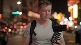 Young happy tourist man backpacker vlogging with phone in Chinatown at night
