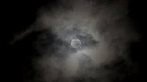 Full moon on dark cloudy night. Clouds passing by the moon in spooky feeling like thriller and horror films. Werewolf moon, dark night sky, black clouds, full moon clouds, ghost, horror films.

