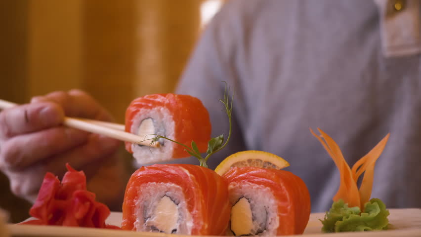Male hands spliting chopsticks for eating sushi roll in Japanese restaurant. 