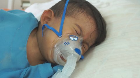 Little boy crying while use making inhalation with nebulizer 