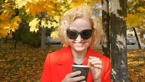 woman in sunglasses drinks the coffee outdoors with autumn yellow leaves