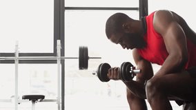 african american sportsman with dumbbell exercising at gym in slow motion