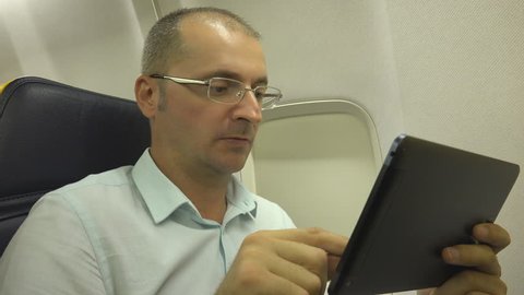 Busy Mature Business Man Working on Digital Tablet Pc Interior Airplane Travel