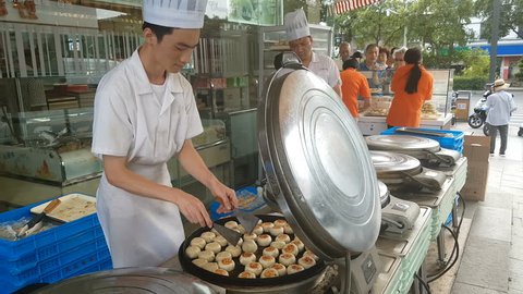 SUZHOU, CHINA - SEPTEMBER 2018: Chefs wearing white uniforms prepare traditional mooncakes, a popular food (desert) for the Mid-Autumn festival celebrations in Suzhou, China