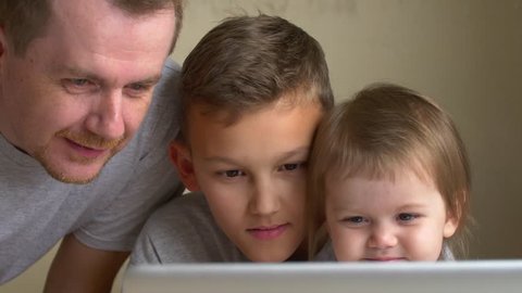 Two children and parent watch video, have fun together. Father, son and daughter look to screen. Man, big brother and small sister learn on laptop. Adult and siblings, boy and girl looking to display
