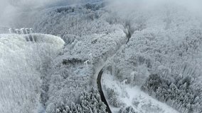 Winter landscape,road and snow covered trees. Aerial view of highway among the forest. Snowy tree branch in a view of the winter forest. Aerial footage, 4K video.
