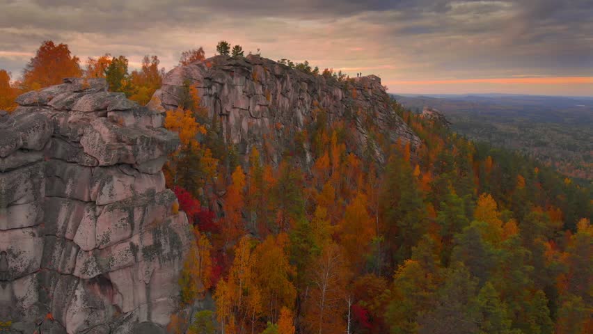Autumn landscape: scenic cliffs covered by colorful forest at sunset. Aerial view in 4K.