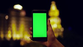Young woman holding phone with vertical green screen