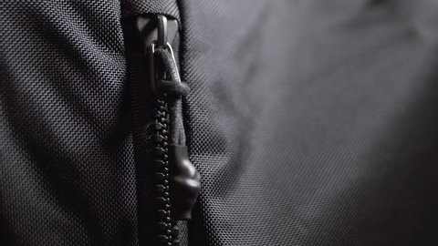 Man unzips and zips black nylon sport backpack bag. Close up shot, 4k.