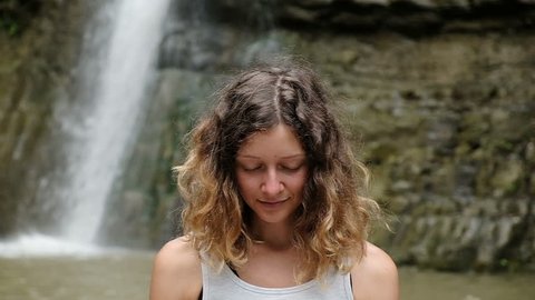 Happy girl meditates and opens her eyes while awakening from the practice, slow motion
