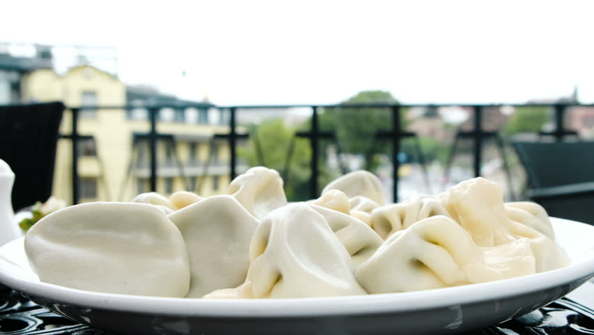 Woman takes khinkali, dumplings, hand in a restaurant in the open air closeup