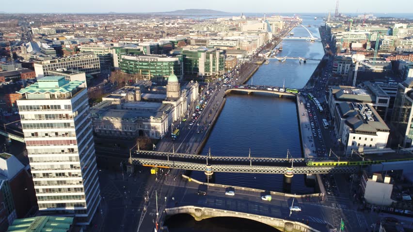 The drone is flying still over the City Centre, looking towards the Dublin port, while a train passes by in the foreground.