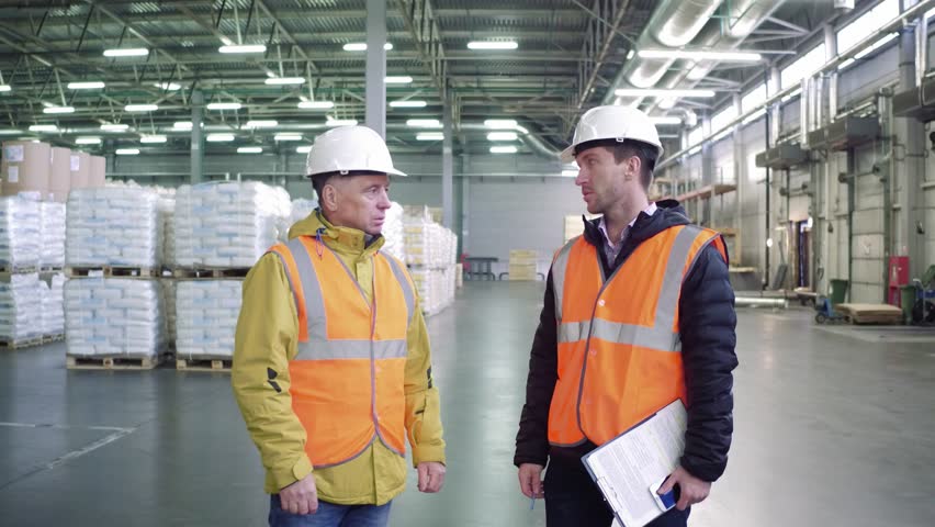 Workers talking , discussing stock inventory standing against tall shelves, copy space. Royalty-Free Stock Footage #1020927775